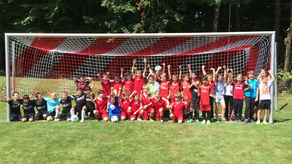 Viele Fussballkinder stehen in einem Tor und jubeln